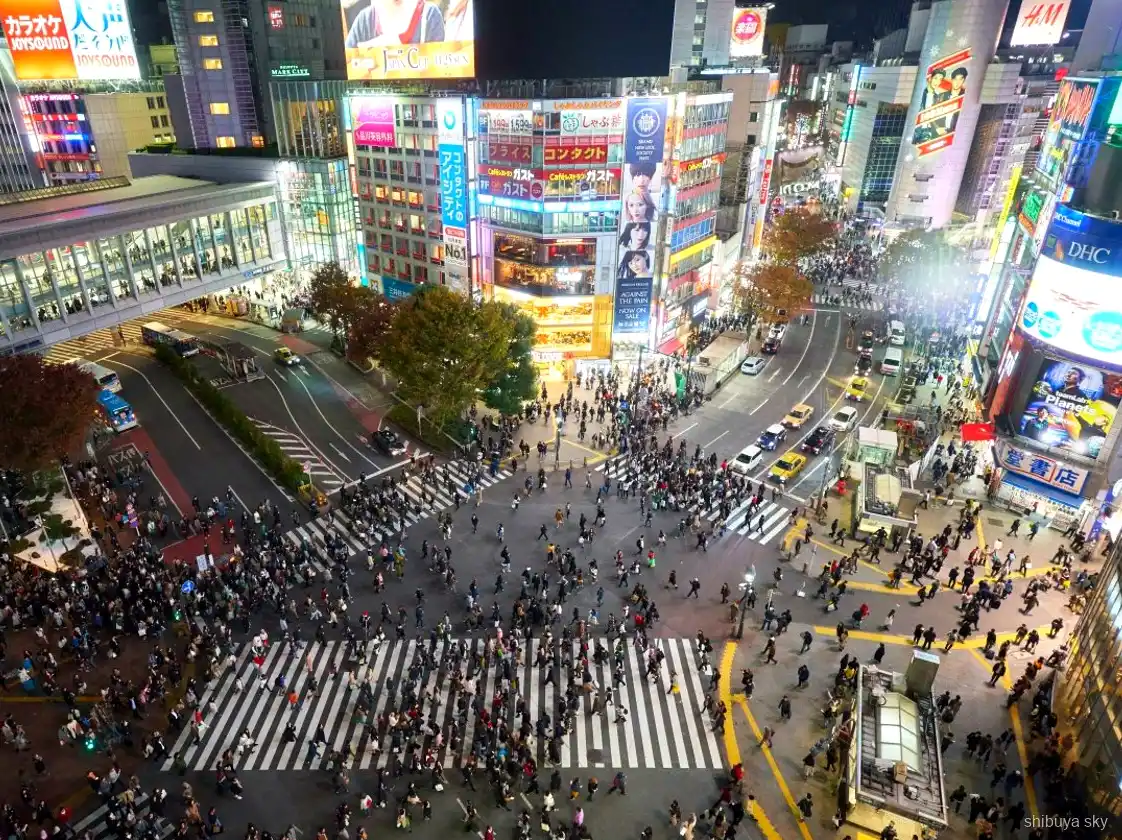 Tour nocturno Shibuya Sky, guía y visitantes en las calles de neón
